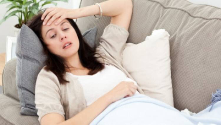 tired woman in early pregnancy lying on couch