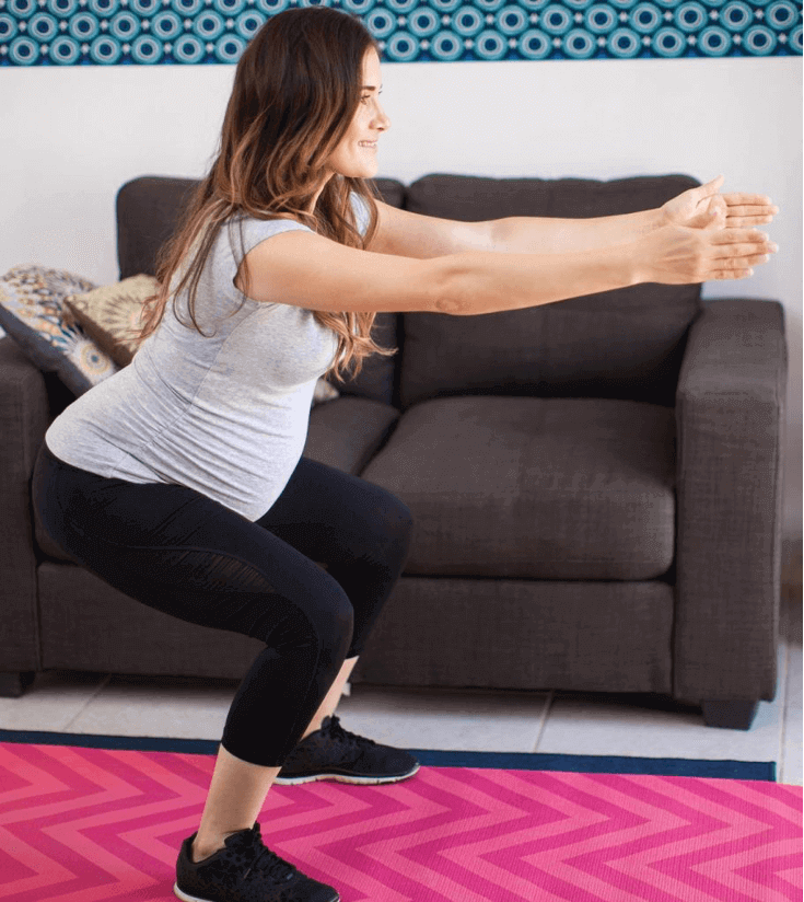 pregnant woman in starting squat position for get ups