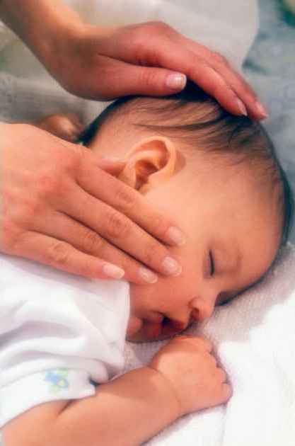 mother gently cradling head of sleeping baby