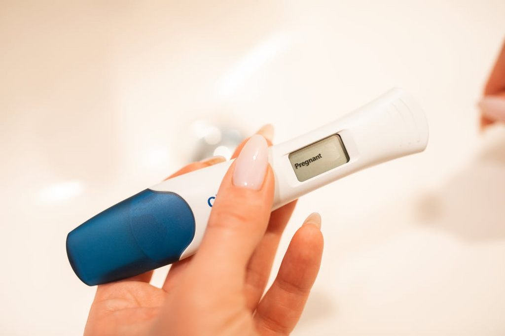woman holding pregnancy test wand showing that she's pregnant