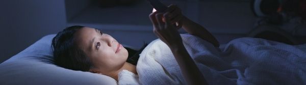 woman on bed looking at mobile phone