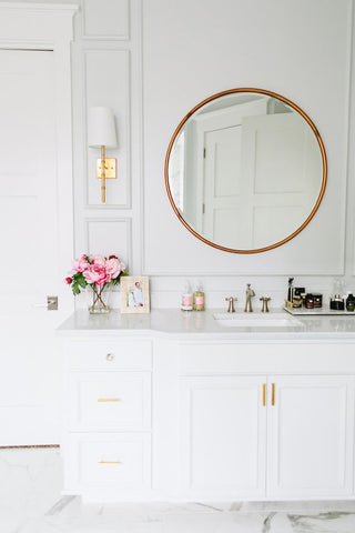 a chic marble slab sink accentuated with bright brass faucets, wall lamps and mirrors