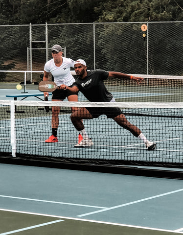 top level pickleball player man reaching for ball to poach from partner