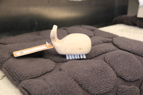 Close up of Whale nail brush sitting on the Battleship grey pebble bath mat