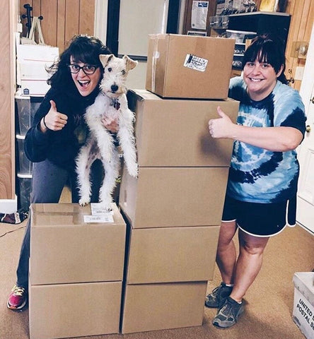 Lauren Beacham and Brittany Elbourn of Yugen Tribe with wire fox terrier dog on pile of package