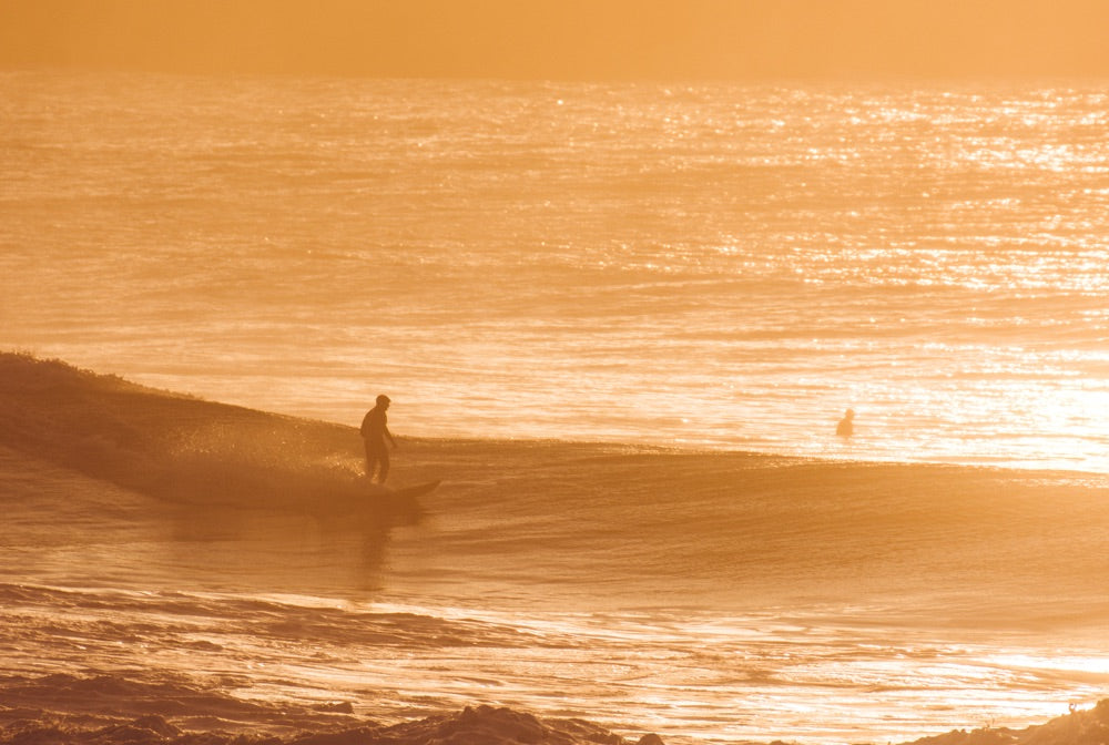 A surfer sits patiently in the water waiting for the next wave to roll through