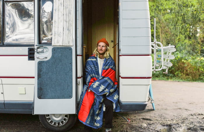 A man sits in a camper wrapped in a nomadic blanket