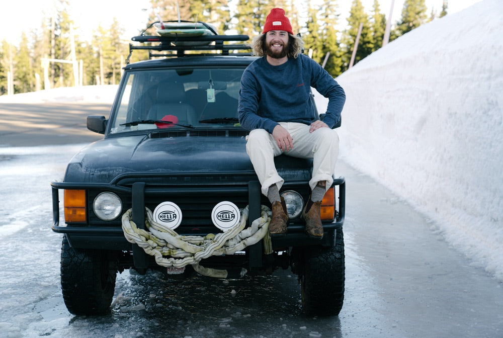Brandon Haley sits on the bonnet of his 4x4 on a snowy road in the Pacific NorthWest