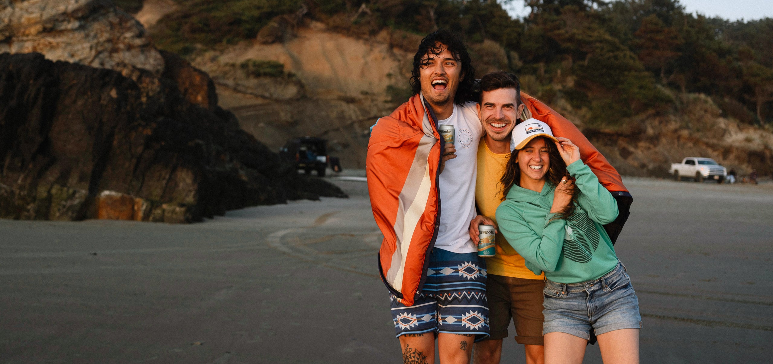 A group of friends stroll along a beach in the Pacific North West enjoying a passenger IPA