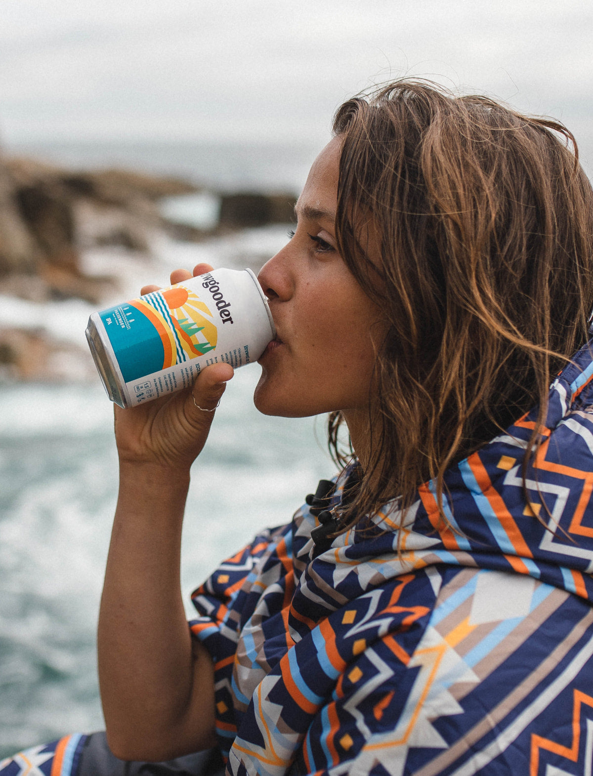 A woman sits on a rock enjoying a Passenger IPA