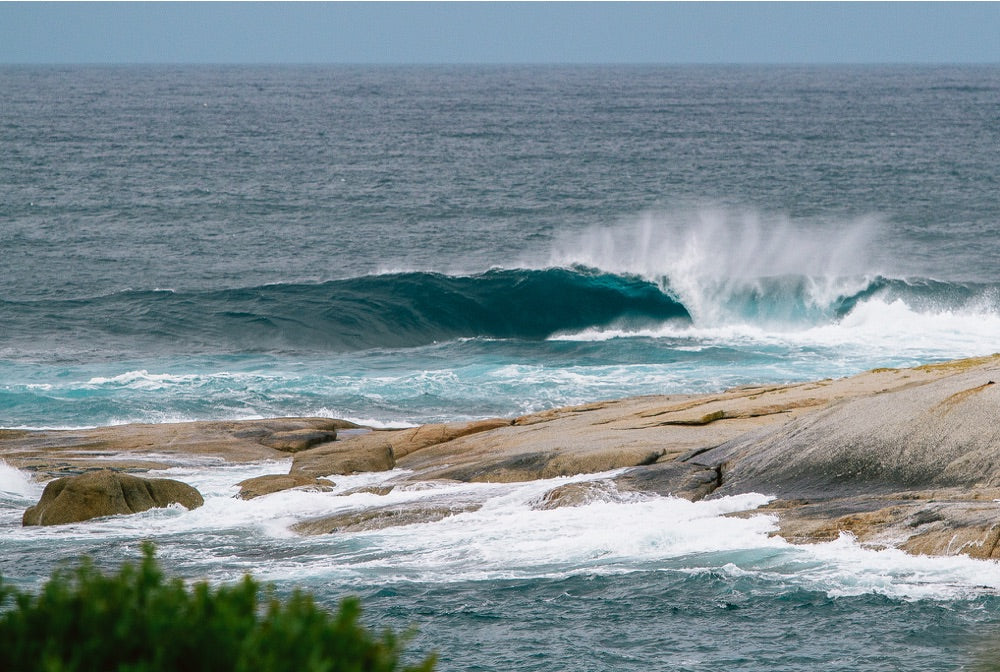 A wave breaks as surfers watch on