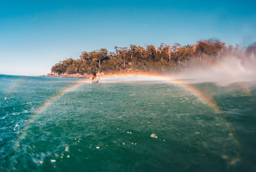 A surfer sits patiently in the water waiting for the next wave to roll through