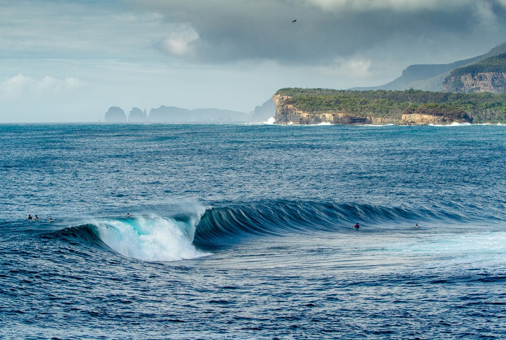 A wave breaks as surfers watch on