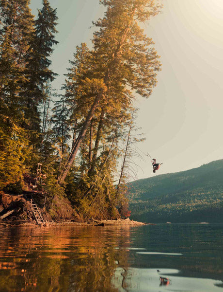 Man back flipping in to the sea from a tree