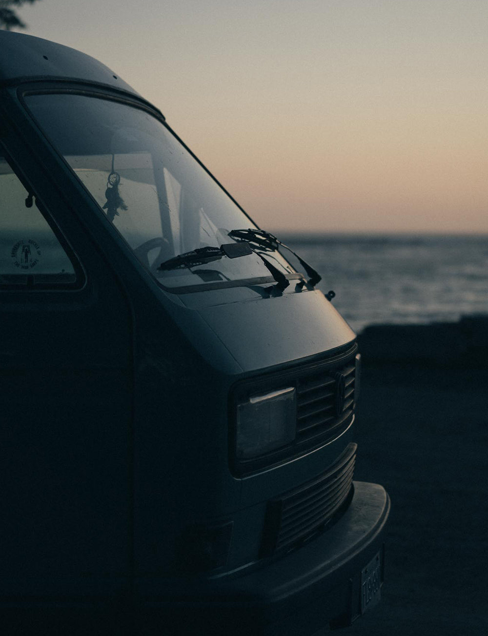 The sunset reflects off the windscreen and bonnet of the classic VW Westy