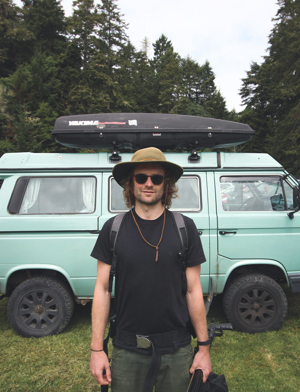 A portrait of Mackenzie Duncan, standing infront of his classic campervan