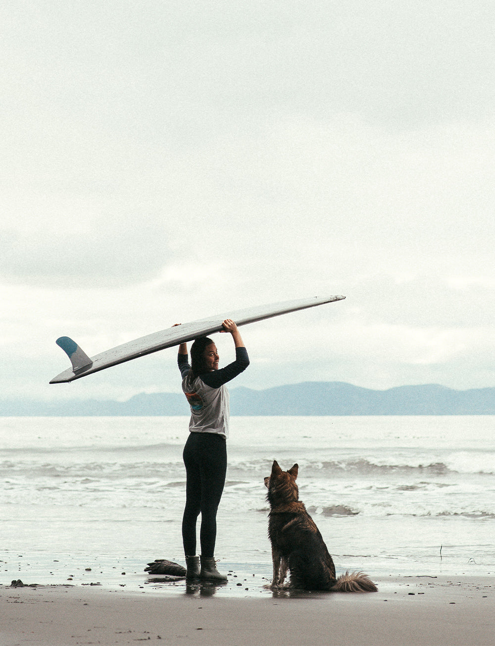 A female surfer with her dog waits for waves