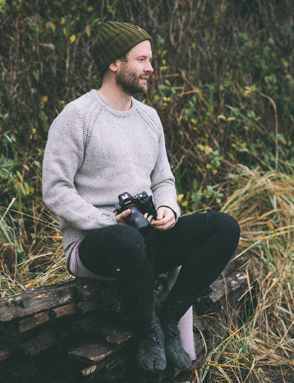 Fotograf sitzt nach dem Surfen und schaut auf die Wellen