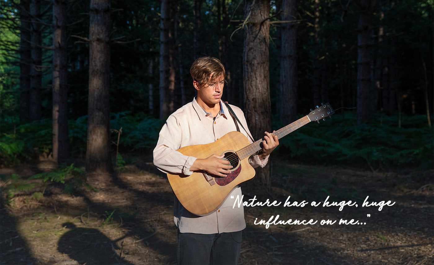 Nathan Ball sings with his guitar in the forest.