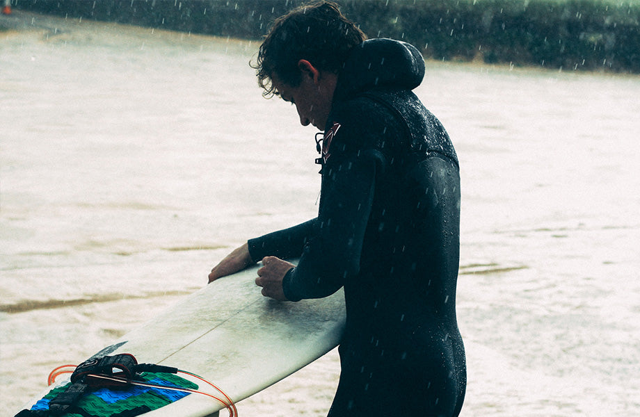 Winter in England waxing surfboard in the rain