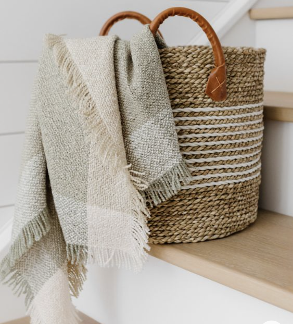 A basket with a throw blanket hanging out.