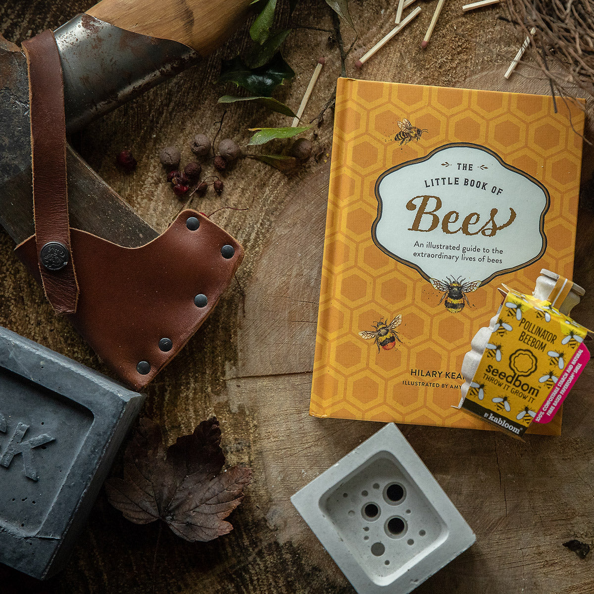 Bee lover gift bundle including bee hotel, book and wildflower seeds, shown on wooden background