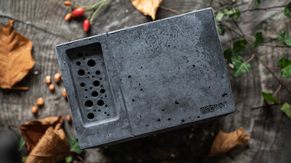 christmas gift for an outdoorsy person person who likes the outdoors a charcoal beepot to house solitary bees can be used as an outdoor feature plant pot. Charcoal beepot in the picture is placed on its back with the bee cell holes facing upwards and surrounded by foliage and fallen leaves on a wood block