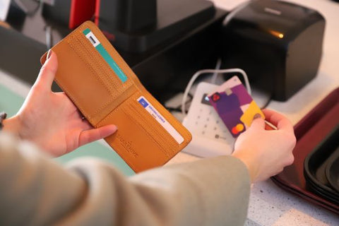 someone paying using a card coming out of a leather wallet