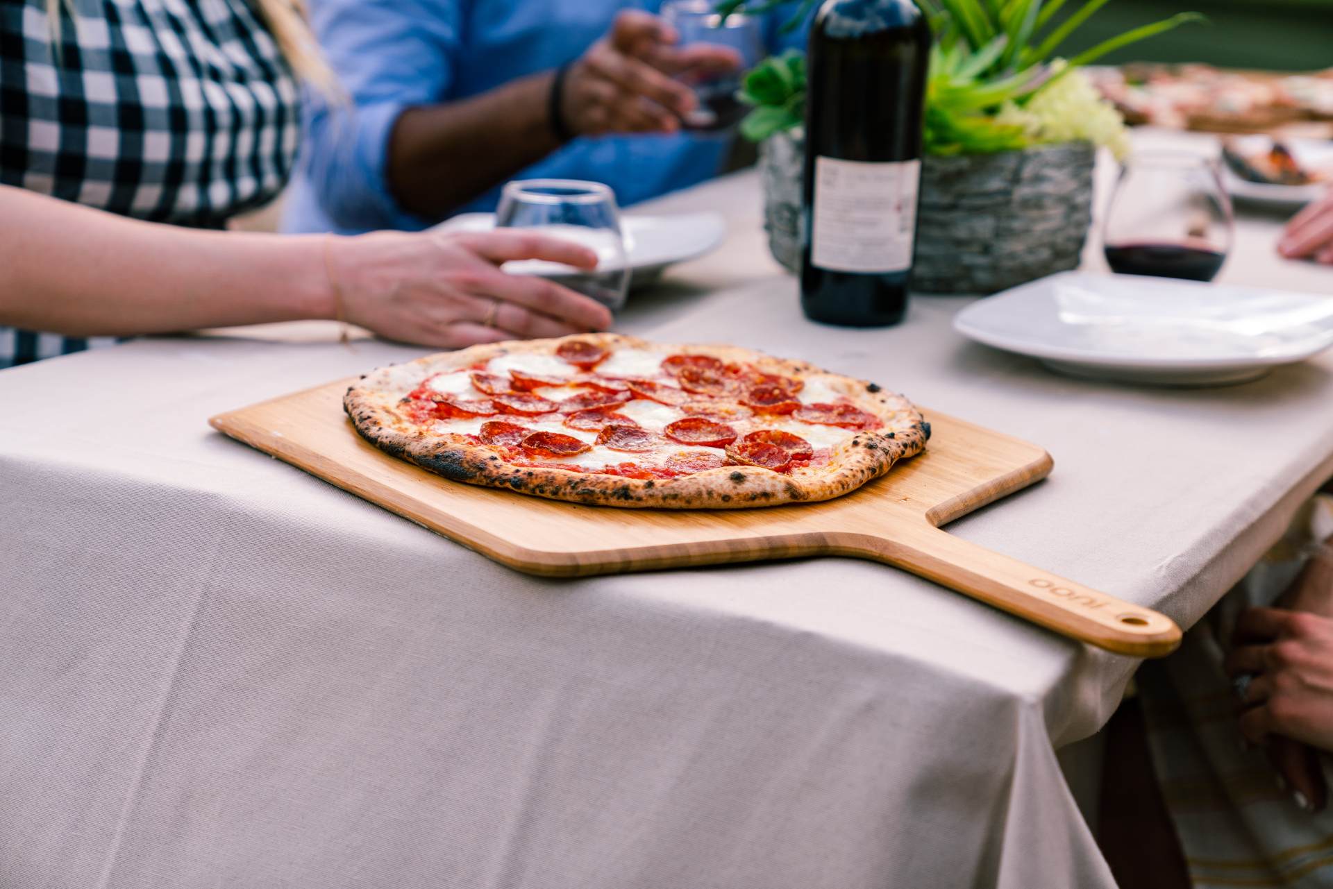 Pizza being served on a wooden bamboo pizza peel