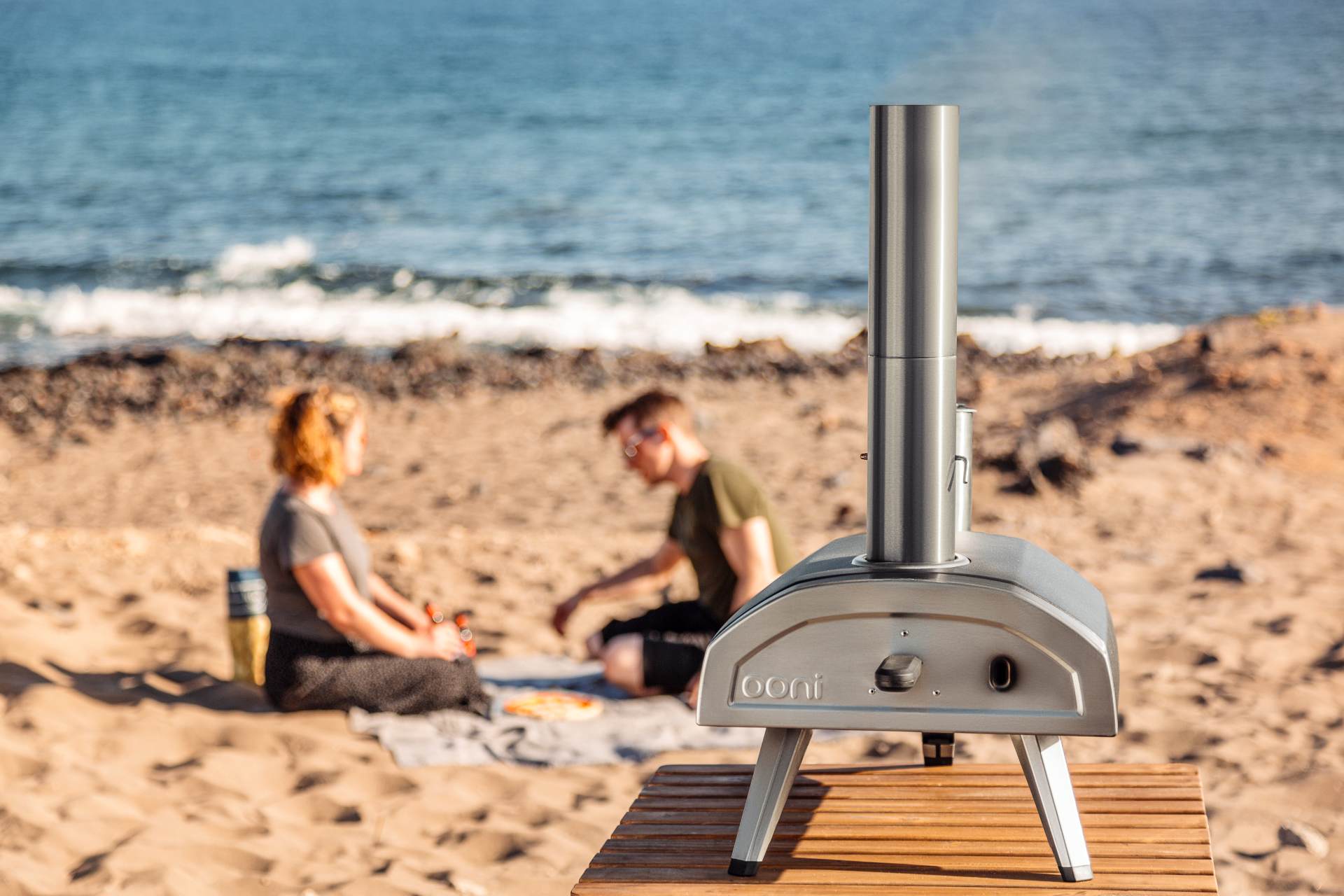 Couple having beach picnic with Ooni Fyra 12