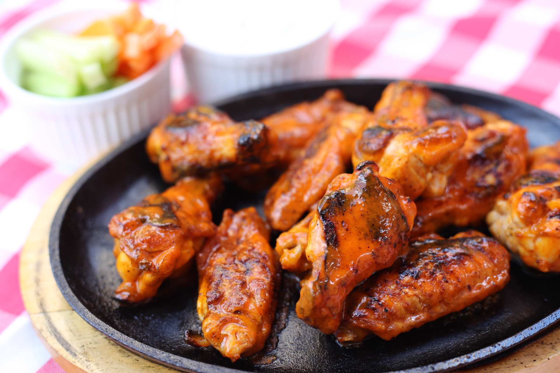 A plate of cooked “over-the-pit” Buffalo wings on a table.