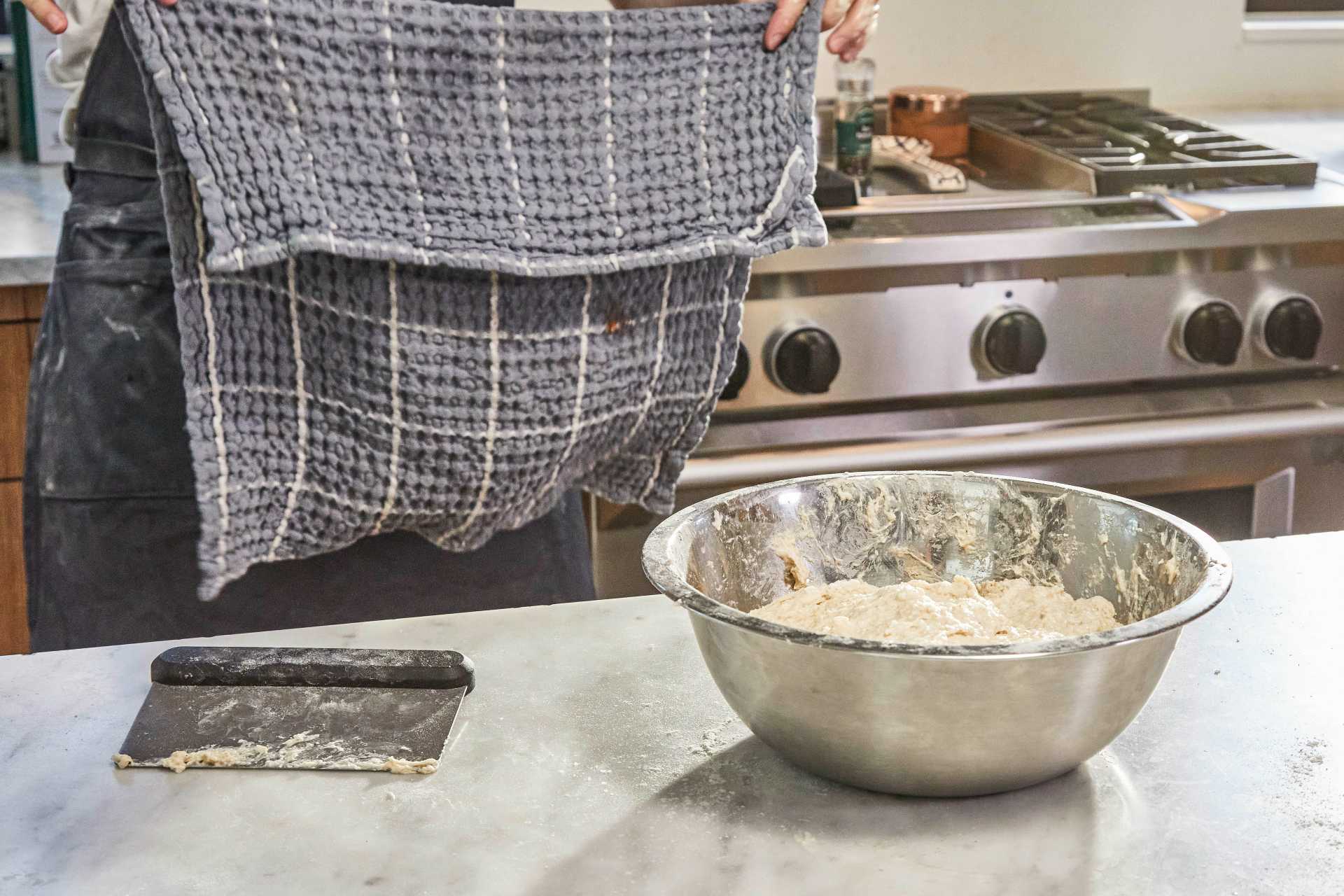 Ramazan Pidesi dough in a metal bowl about to be covered with a tea towel