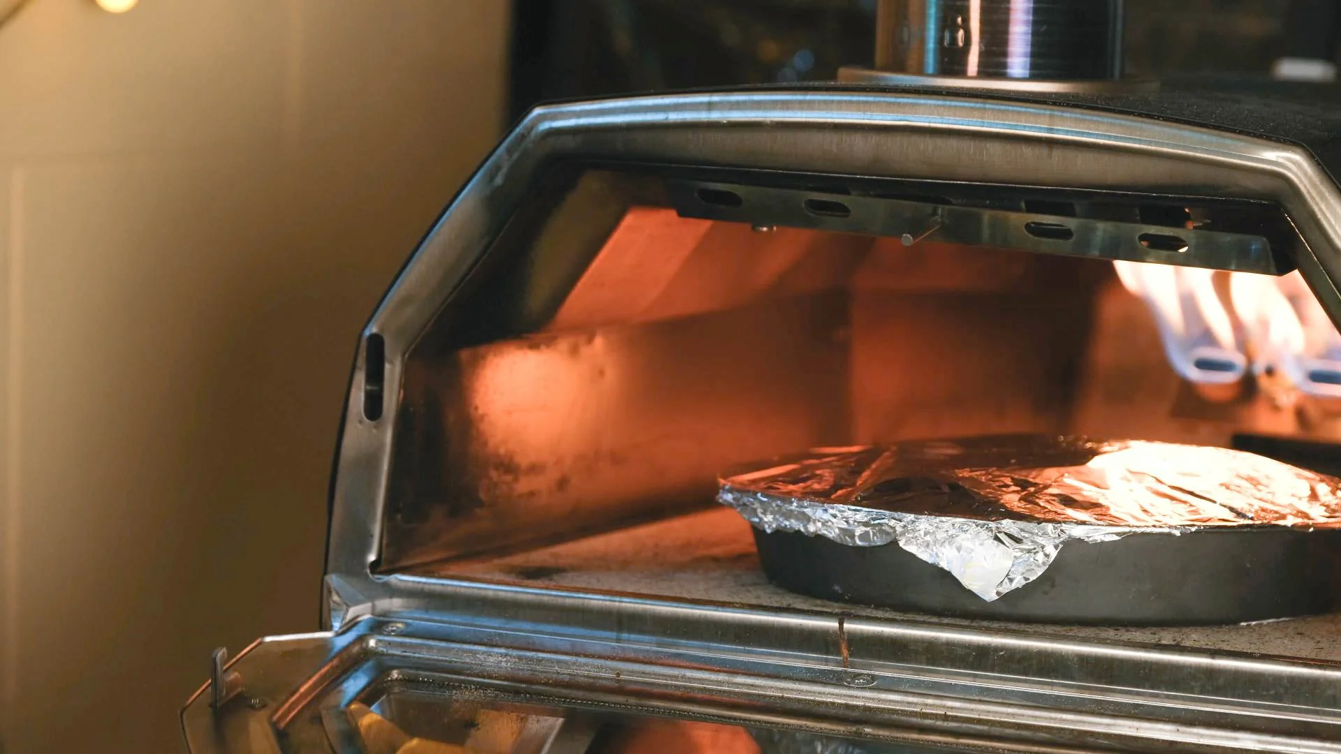 Torta pasqualina covered in tin foil in a cake tin being cooked in an Ooni Karu 16 pizza oven