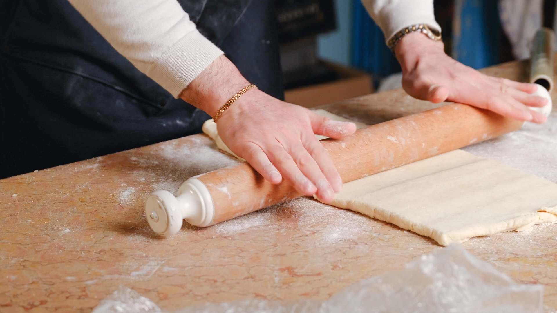 Pastry being rolled out with a wooden rolling pin