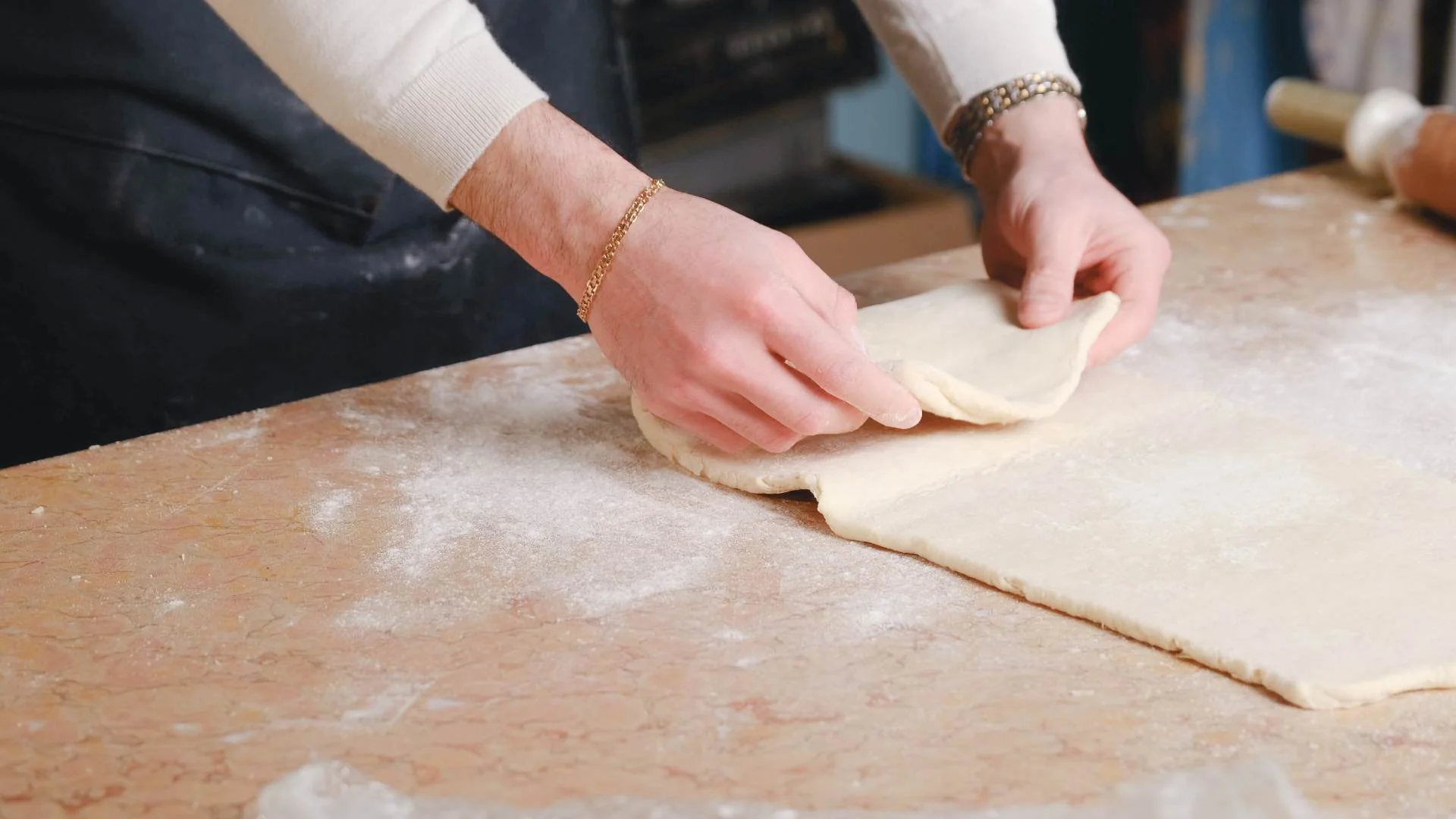 Pastry being folded over on itself on a wooden worktop