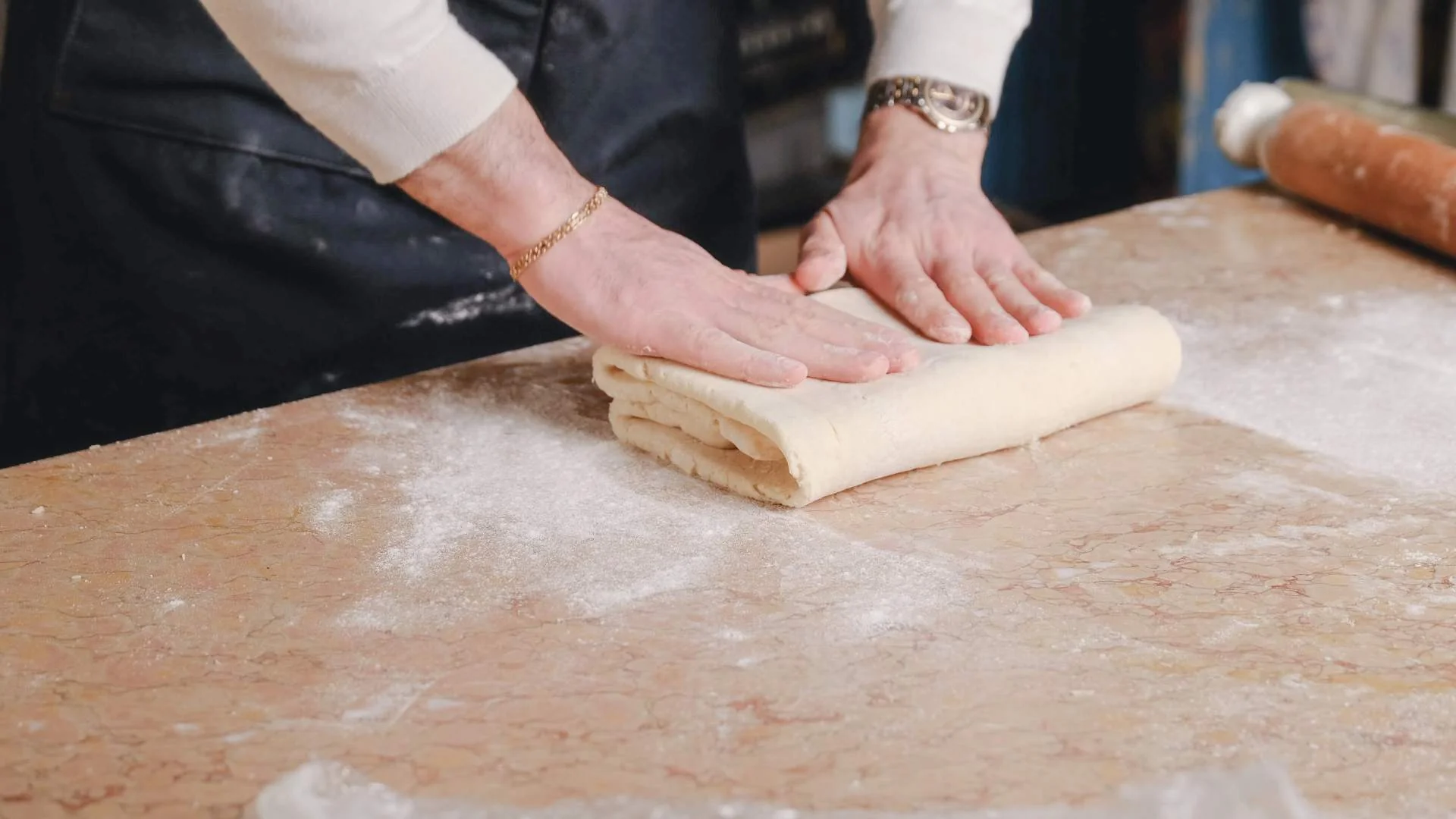 Pastry being rolled over like a book on a wooden worktop