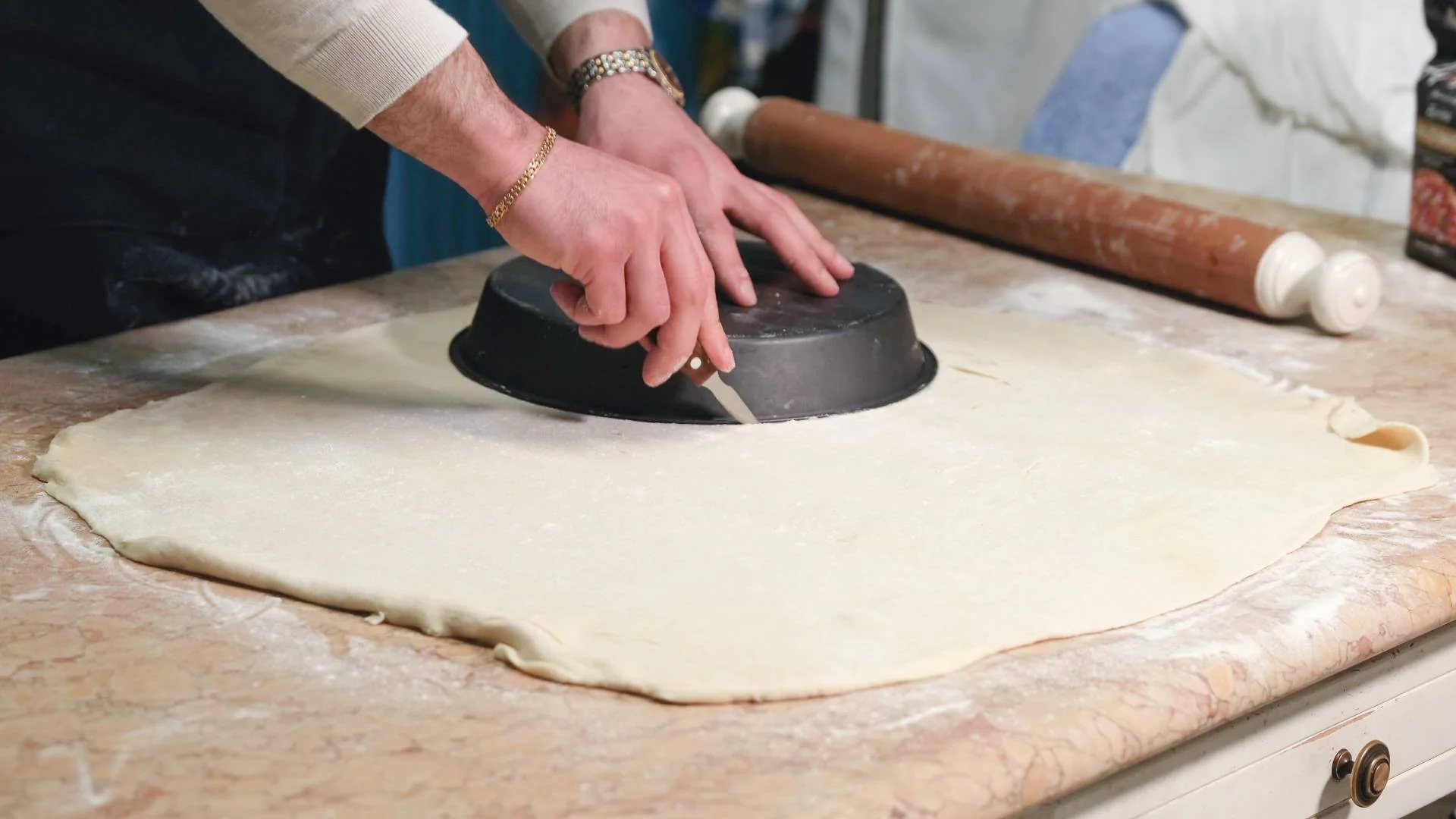 Pastry being cut into a circle with a cake tin