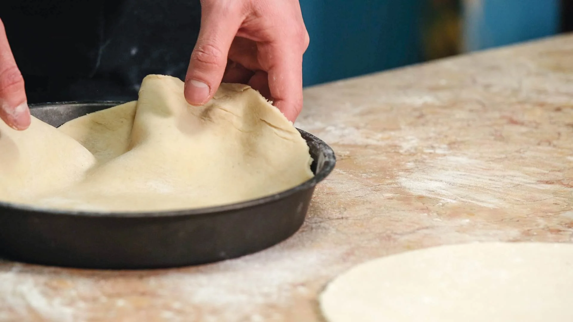 Piece of pastry being placed into a circular cake tin