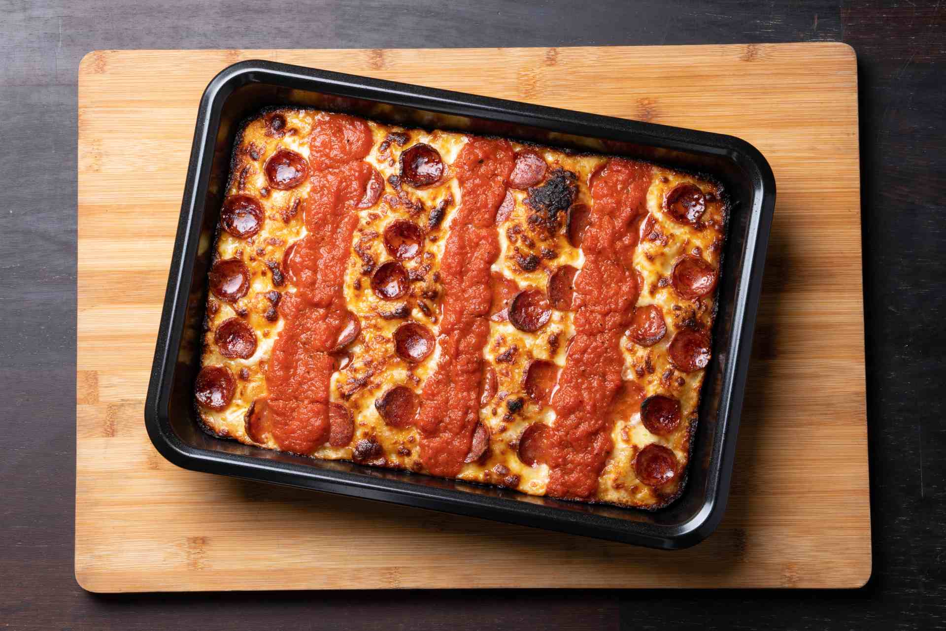 Detroit-style pizza with pepperoni and tomato sauce racing stripes.