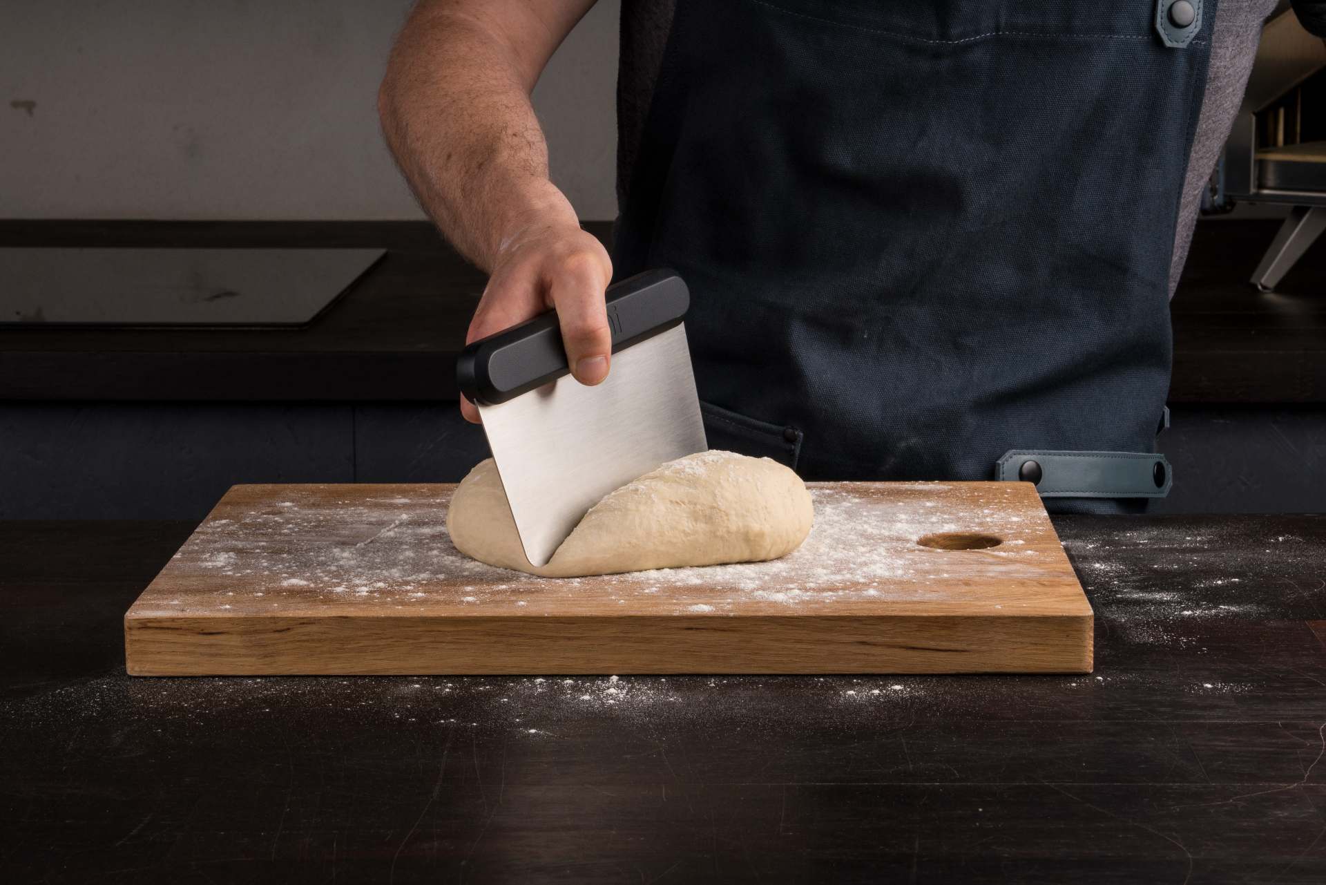 a man uses a dough scraper tool to divide a ball of dough