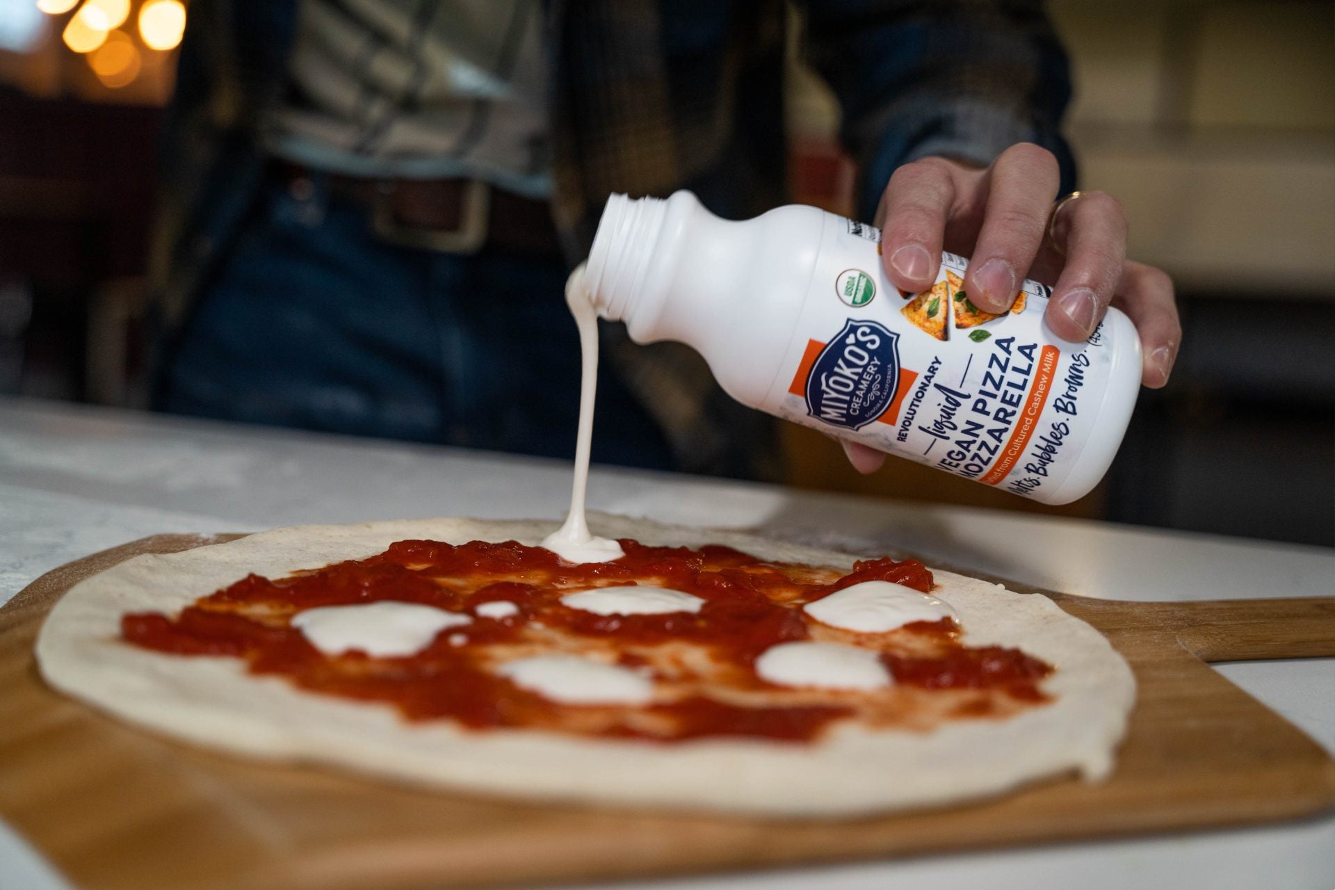 liquid vegan mozzarella being poured on a pizza base