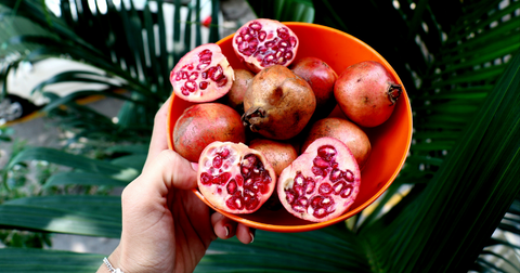person holding a bowl of peeled open ripe and juicy pomegranates