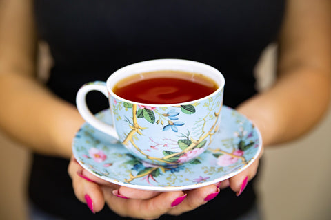 Woman holding a cup of tea with a saucer