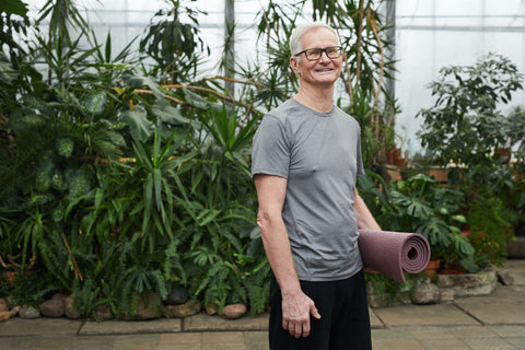 Man standing while holding a yoga mat