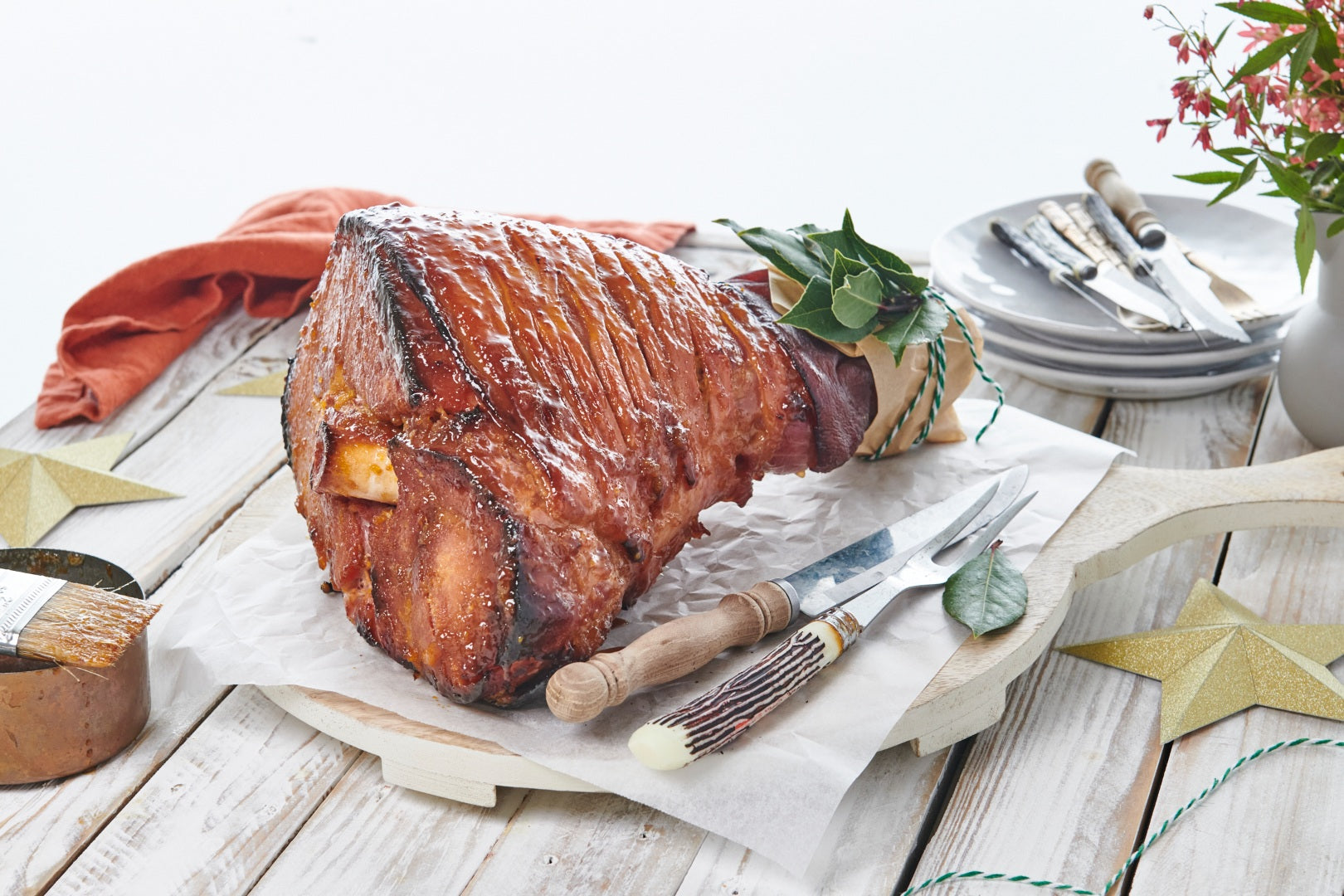A scored, glazed and baked Christmas Ham on a board ready to be sliced and served