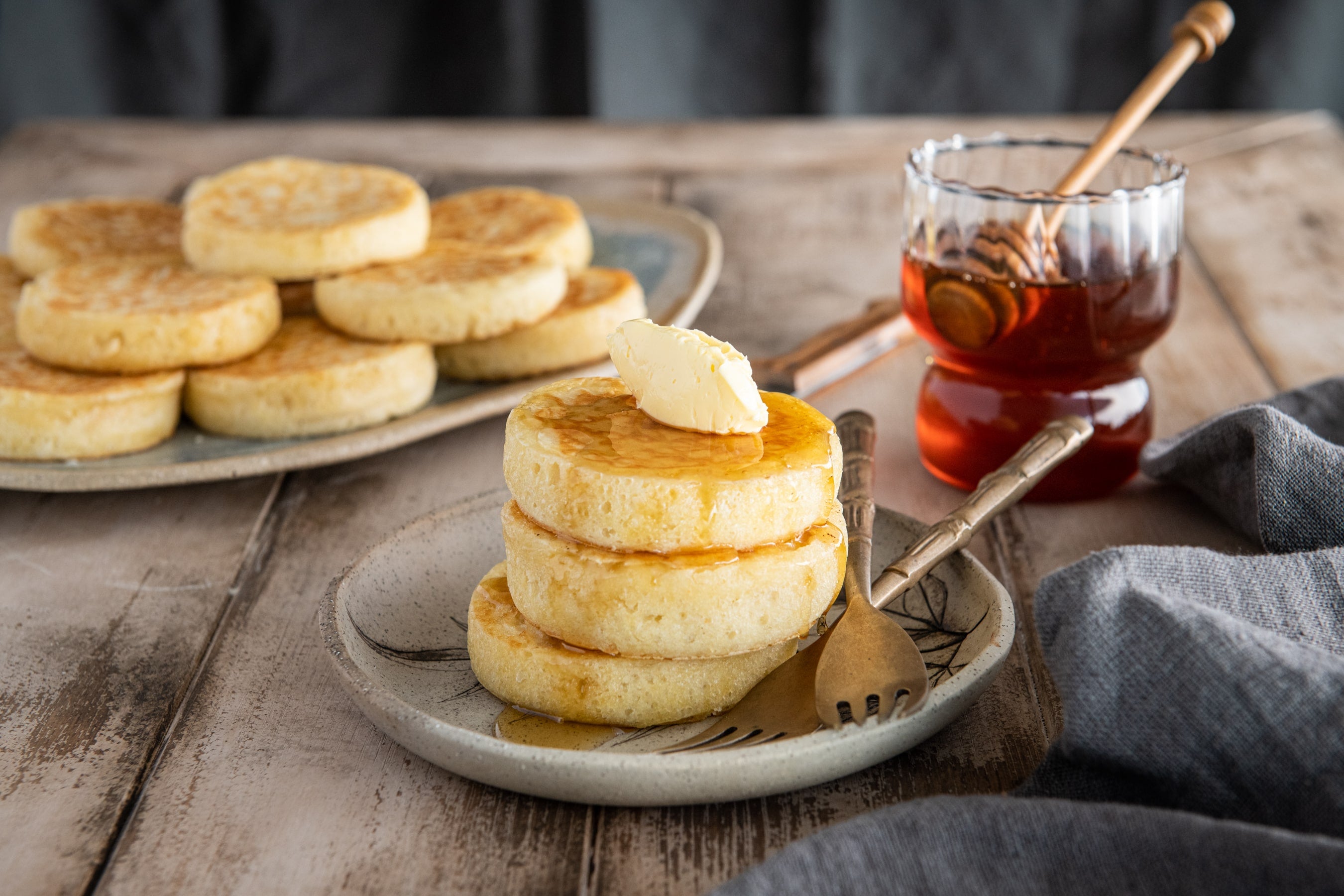 Stack of crumpets with butter on top.