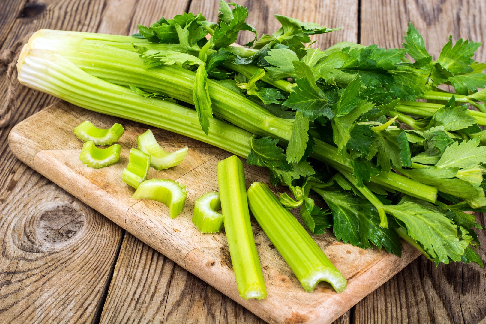 A head of celery on a wooden chopping board
