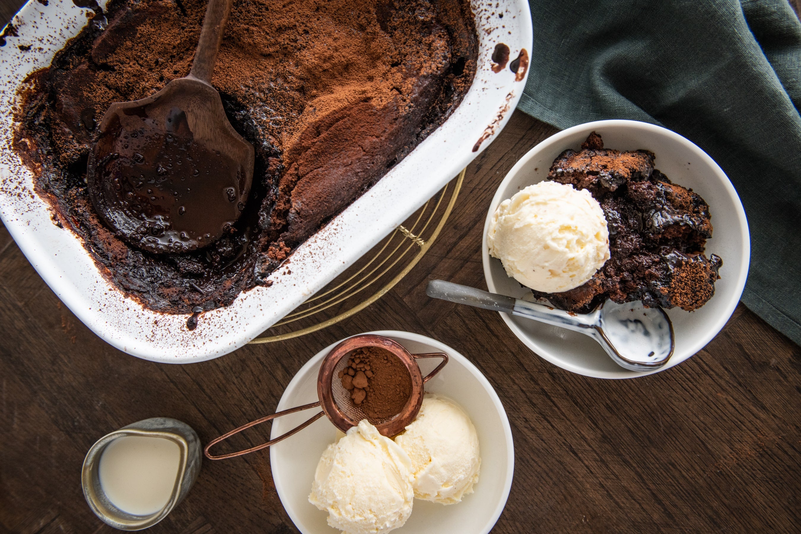 Chocolate self saucing pudding with a slice in a bowl with a scoop of ice cream.
