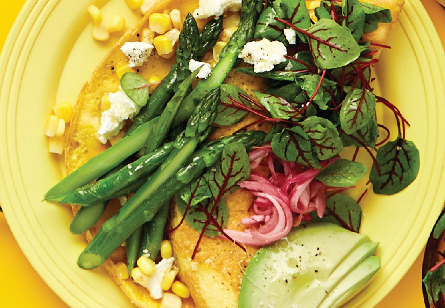 A corn omelette with feta, asparagus, avocado and red onion