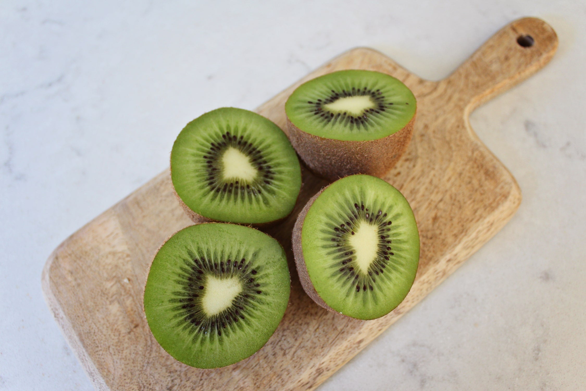 4 green kiwifruit halves on a wooden serving platter